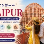 A couple is standing at roof top restaurant and seeing the hawa mahal in a dress that is good for summer jaipur